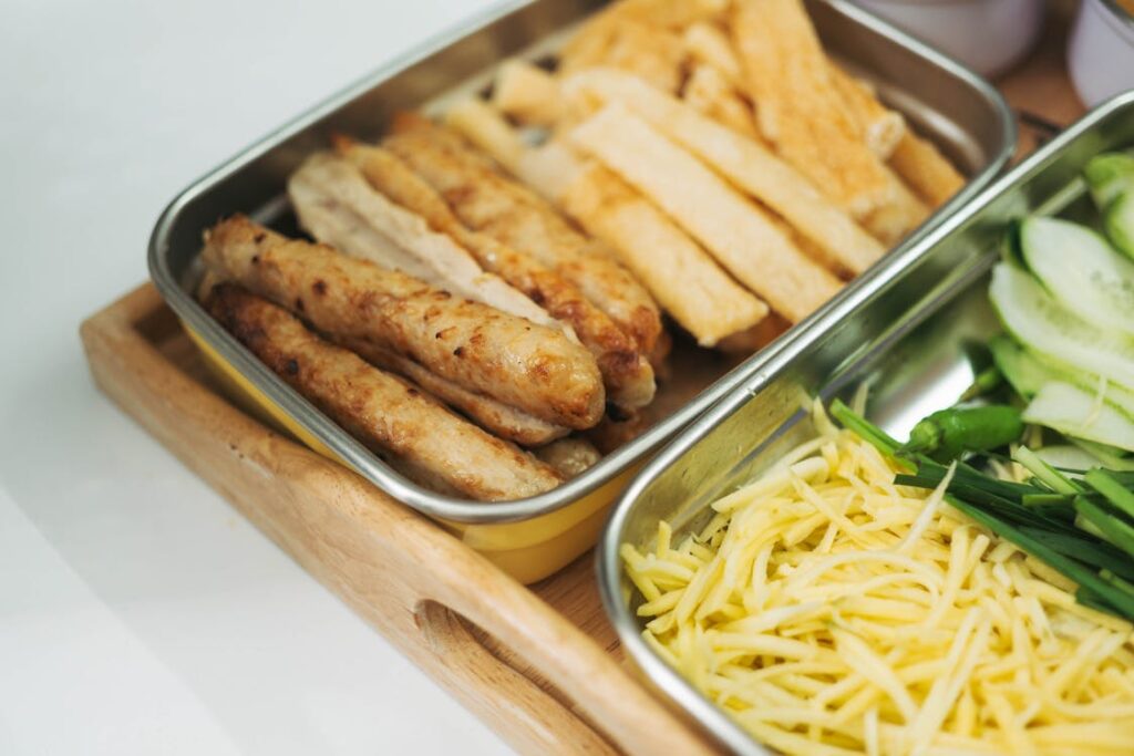 Free Tray with fried sausages and vegetables like cucumber and shredded cheese for a fresh meal. Stock Photo